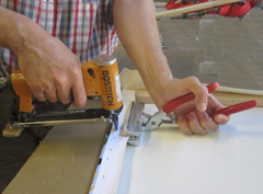 Canvas pliers are used to stretch the canvas, while a staple gun staples it in place